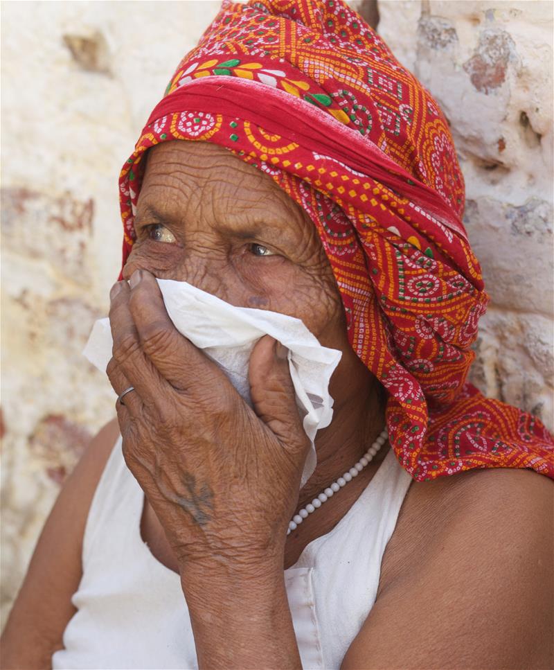 A woman uses a hankerchief outside her home in a Delhi slum.